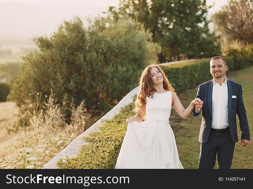 Beautiful long-haired bride in white dress with her young men walking in the nature. Beautiful long-haired bride in white dress with her young men walking in the nature