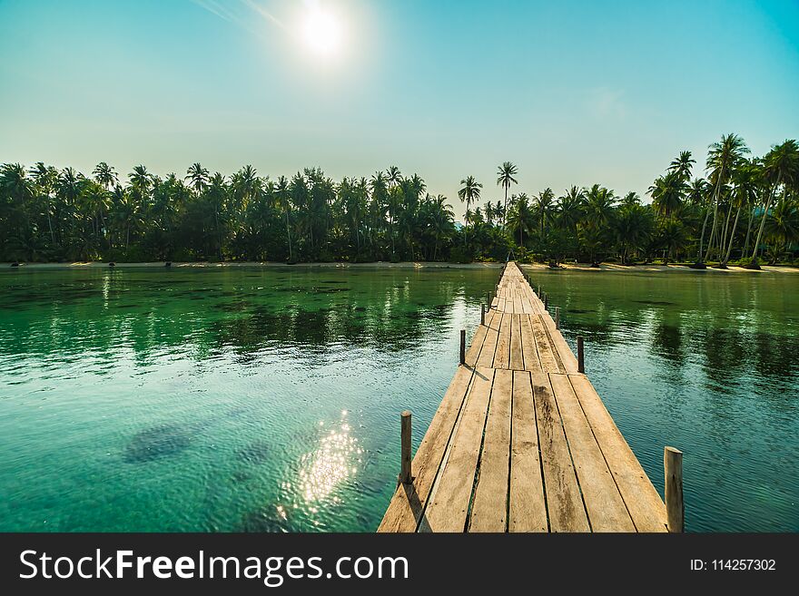 Wood bridge or pier on the beach and sea in paradise island around with coconut palm tree - Holiday Vacation and Travel concept