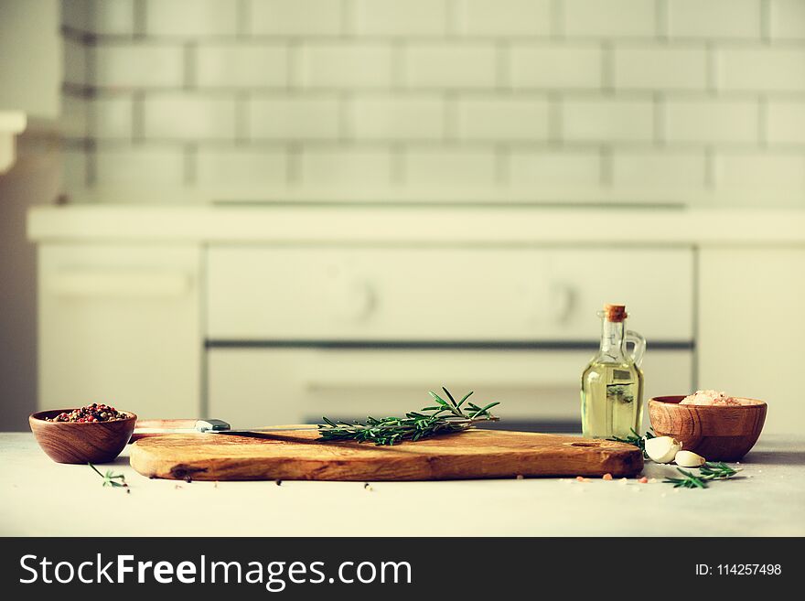 Food cooking ingredients on white kitchen design interior background with rustic wooden chopping board in center, copy space.