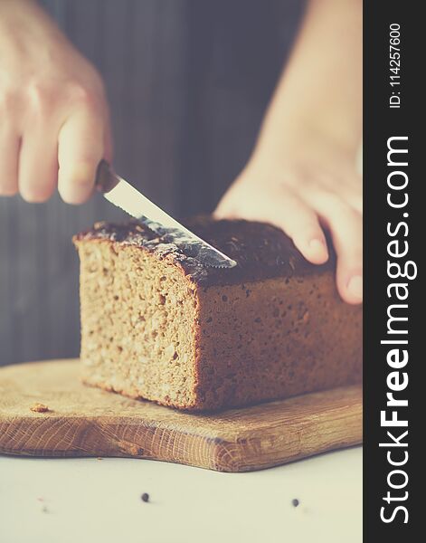 Woman hands slicing freshly backed bread. Handmade brown loaf of bread, bakery concept, homemade food, healthy eating