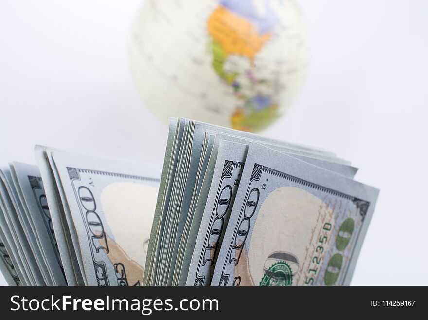 American dollar banknotes by the side of a model globe on white background