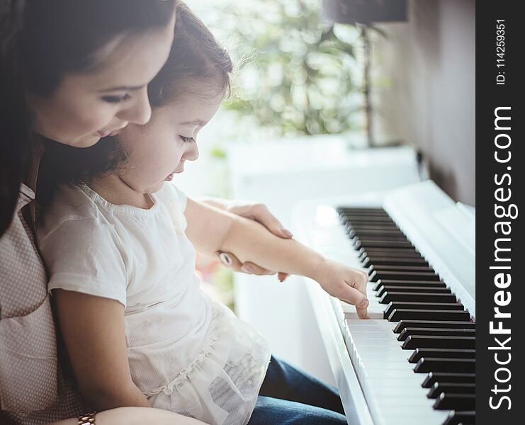 Mom teaching her daughter piano playing