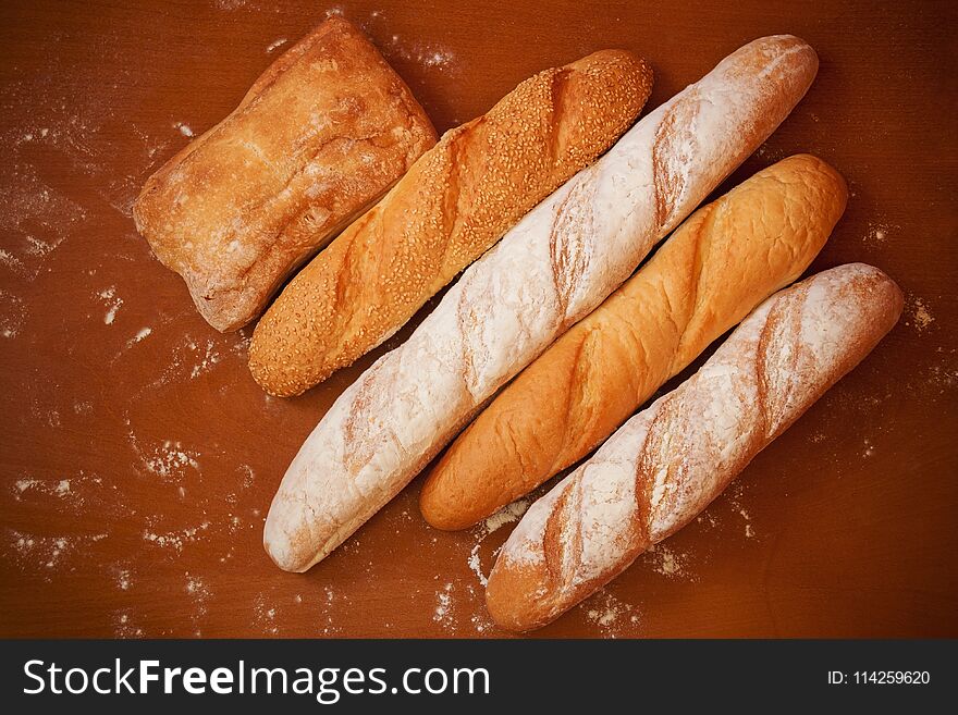 Assortment of baked bread on wooden background. Top view.