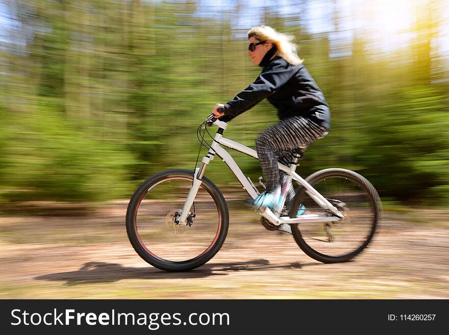 Woman riding a mountain bike on a forest path.