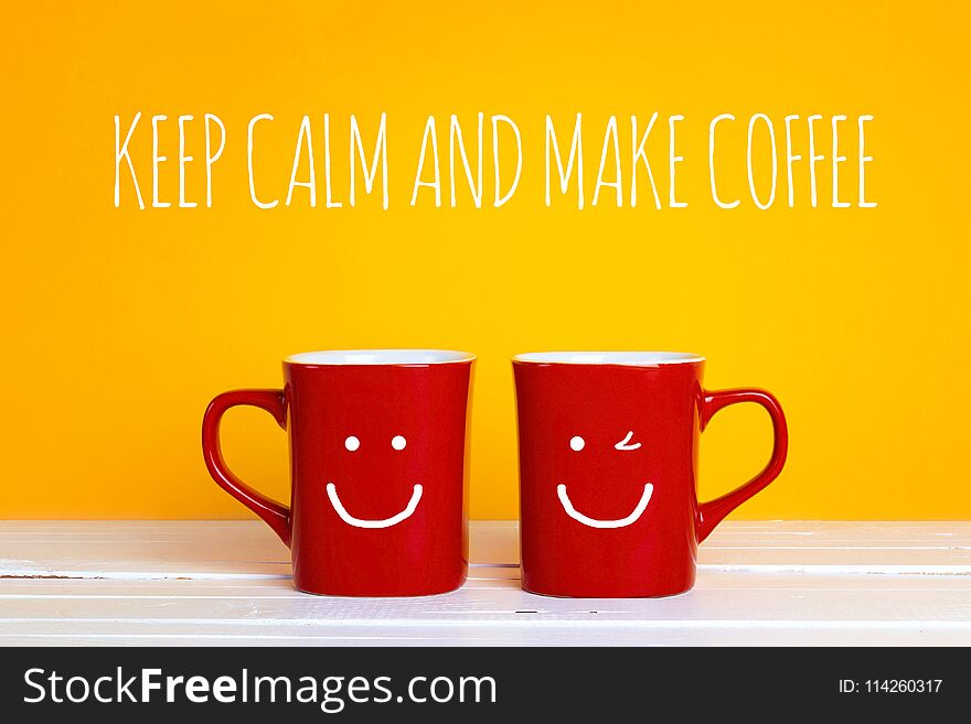 Two red coffee mugs with a smiling faces on a yellow background with the phrase Keep calm and make coffee. Happy coffee mugs.