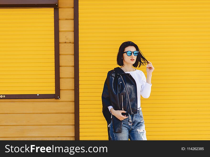 Beautiful girl sunglasses on bright yellow background outside