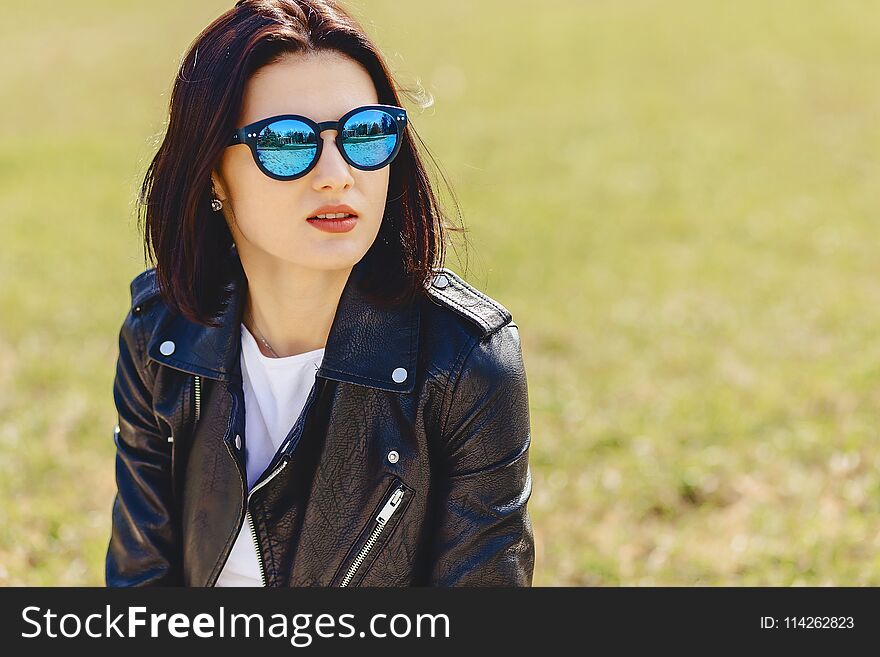 Attractive young girl in sunglasses on grass in park