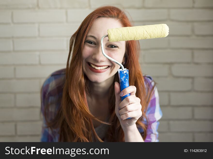 Photo of a red-haired girl in a bright t-shirt that holds brushes for drawing
