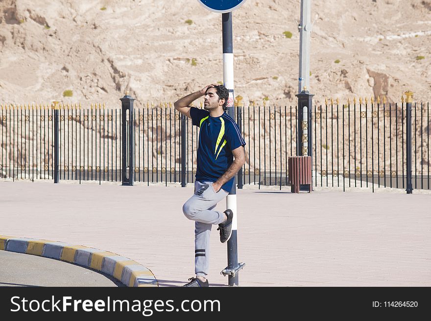 Man Wearing Blue Crew-neck Shirt Leaning On Street Post