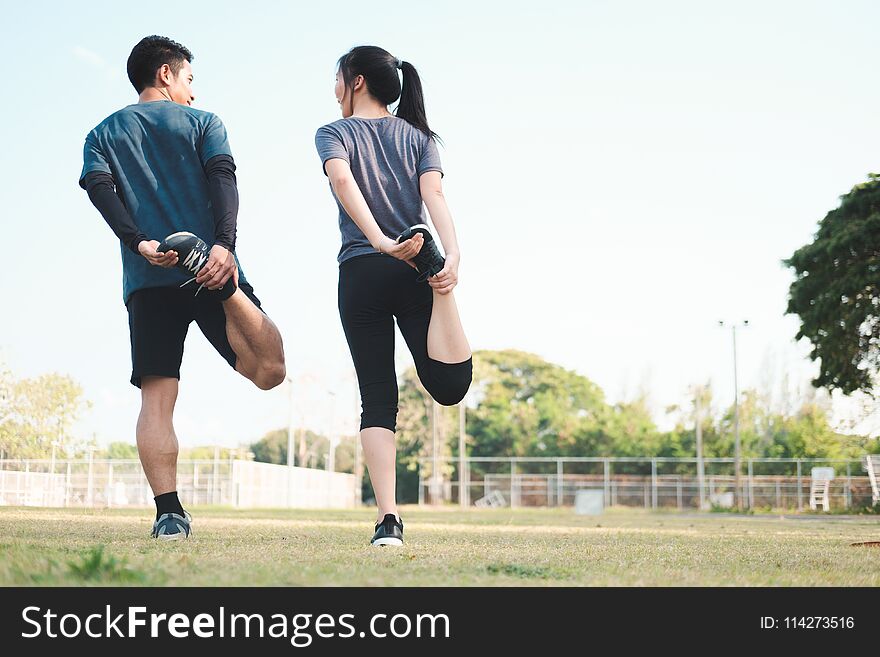 Young men and women stretching in the park. Young couple warming up in morning. Young men and women stretching in the park. Young couple warming up in morning.