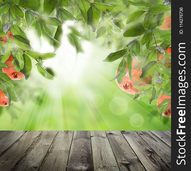 Pomegranate fruit and green leaves on abstract background with gray empty wooden table