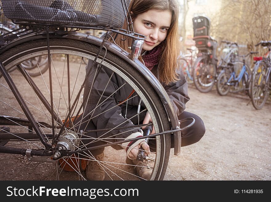 Young woman pumps up the tires of her bike