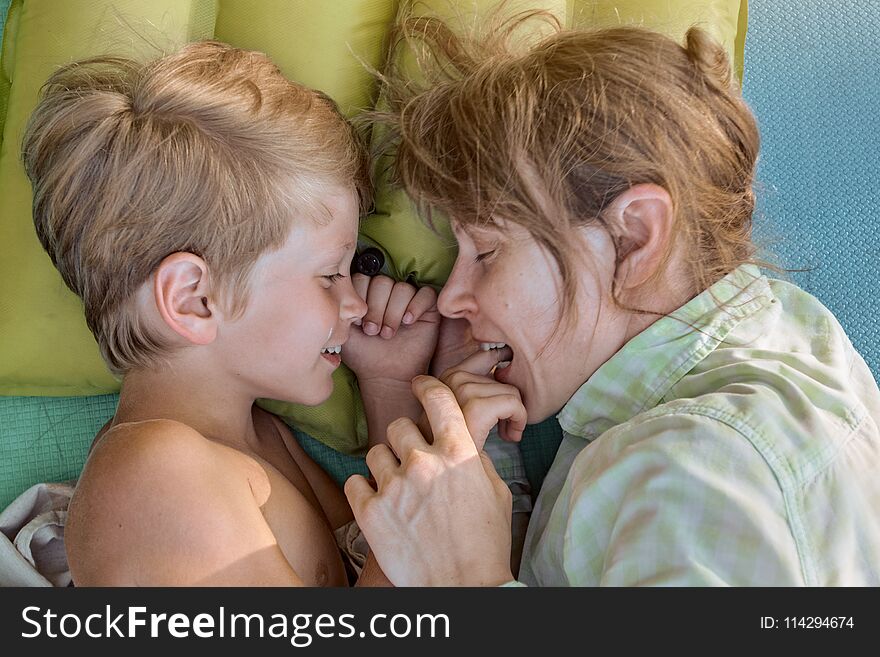 Cute little boy resting with his mom and lying outdoor on mat. Cute little boy resting with his mom and lying outdoor on mat