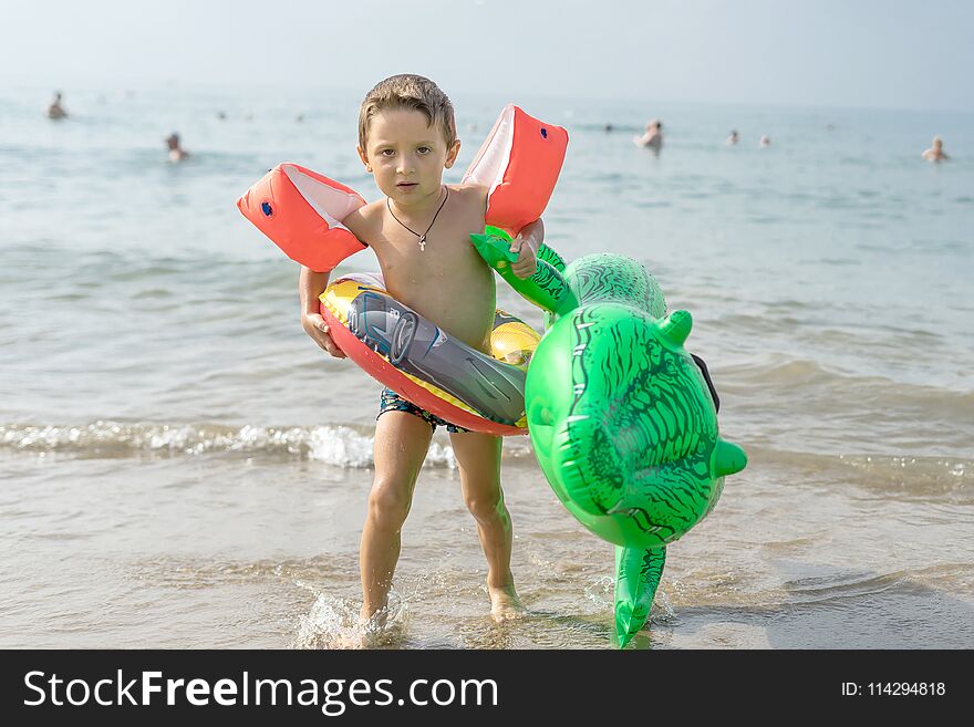 Happy smiling little boy run play with waves on beach. Italy. Summer sea