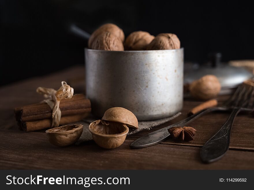 Walnuts In A Metal Bowl, Dark Background. Walnut Shell And Cinnamon On The Wooden Table.