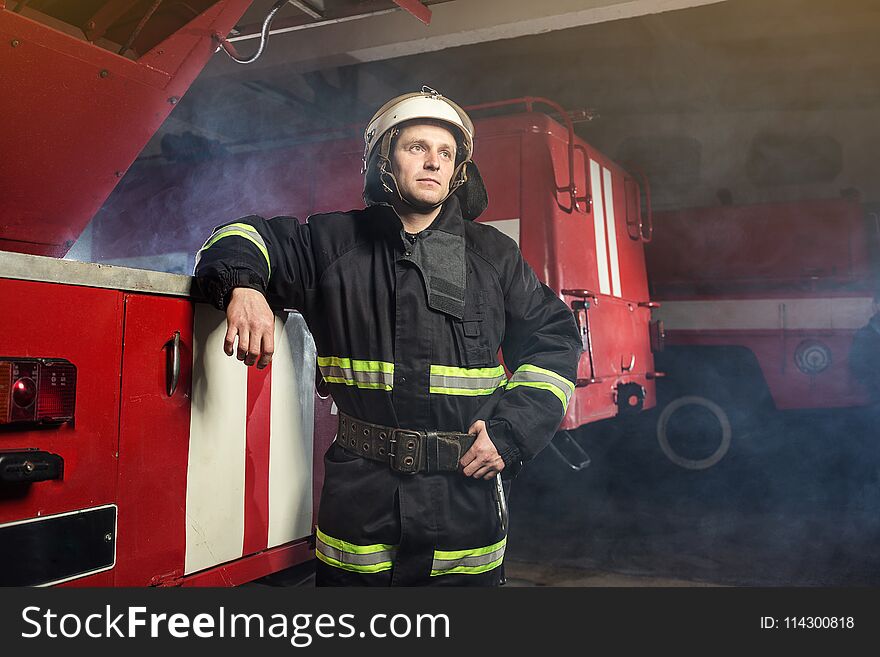 Fireman firefighter in action standing near a firetruck. Emergency safety. Protection, rescue from danger.