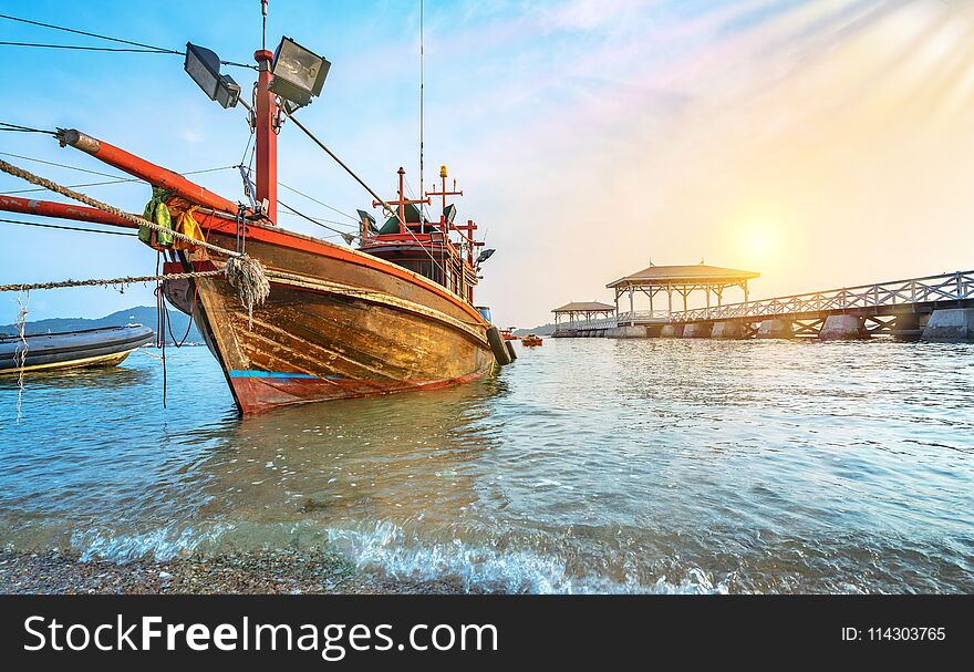 fishing boat on a beach with white wooden bridge at sunrise