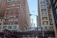 Train Passing By In Downtown Chicago And Airplane Flying Overhead Royalty Free Stock Images
