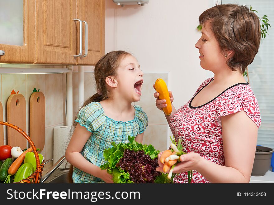 Mother and daughter with basket of vegetables and fresh fruits in home kitchen interior - healthy food concept