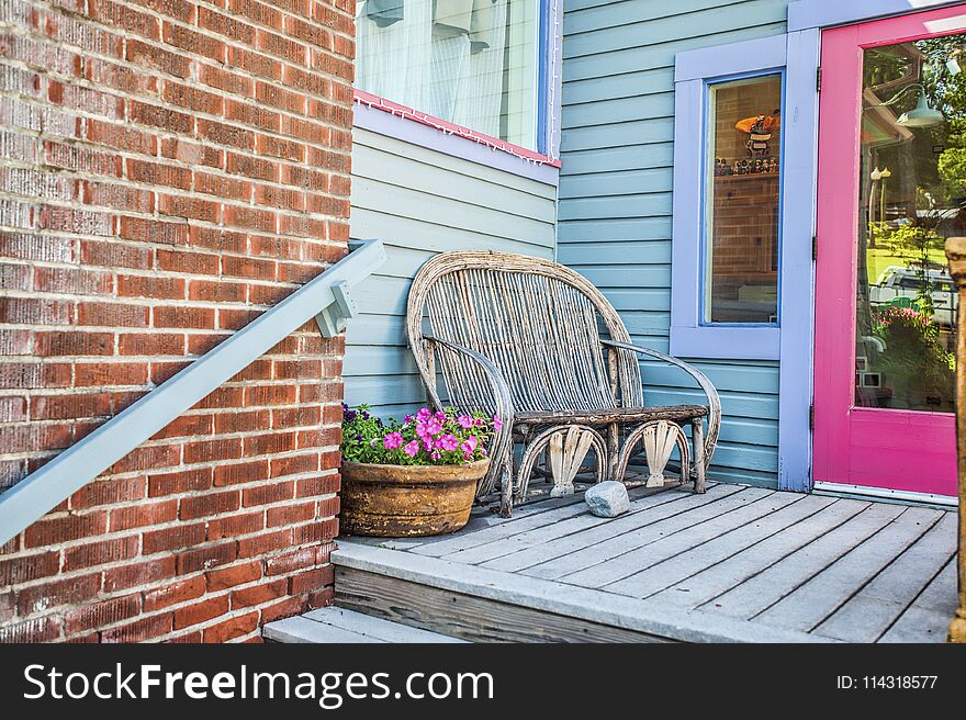 An inviting back porch entrance with a bench and pot of pink petunia flowers. An inviting back porch entrance with a bench and pot of pink petunia flowers.