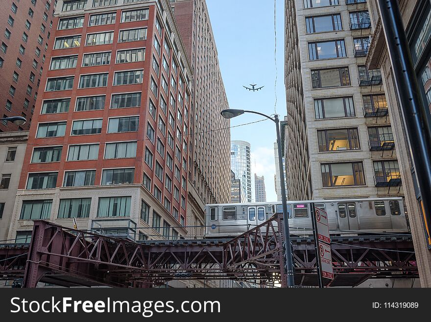 Train passing by in downtown Chicago and airplane flying overhead