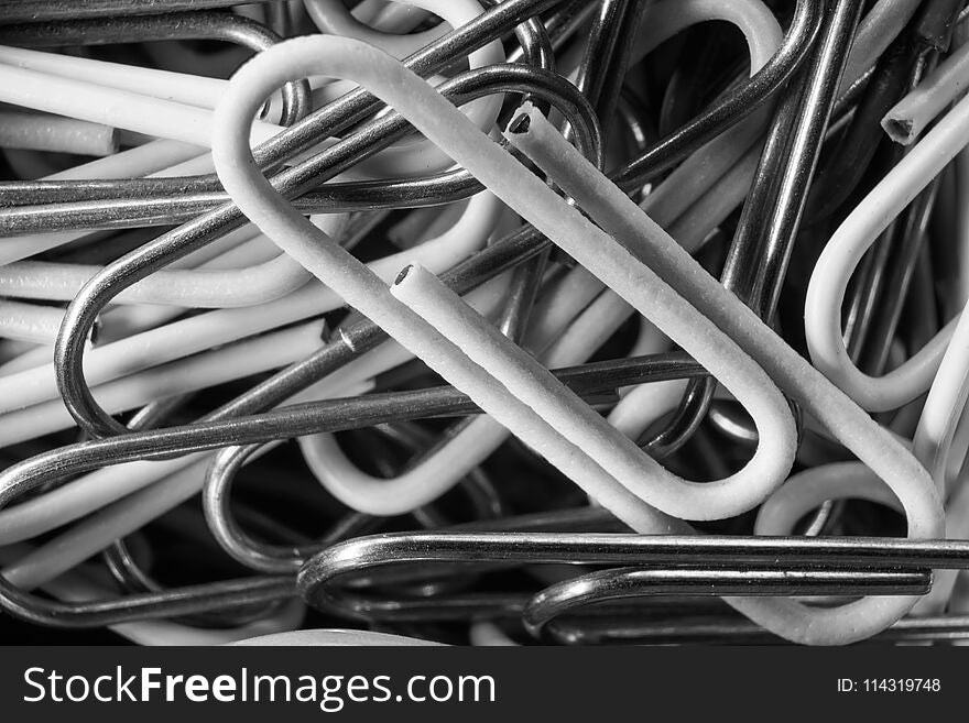 Black and white background of metal and plastic paper clips macro