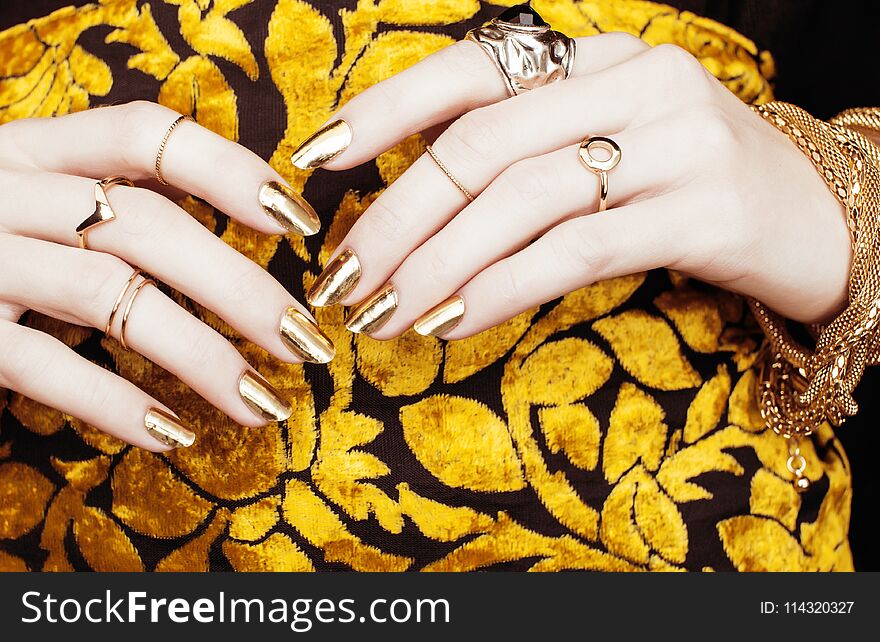 Woman hands with golden manicure lot of jewelry on fancy dress c