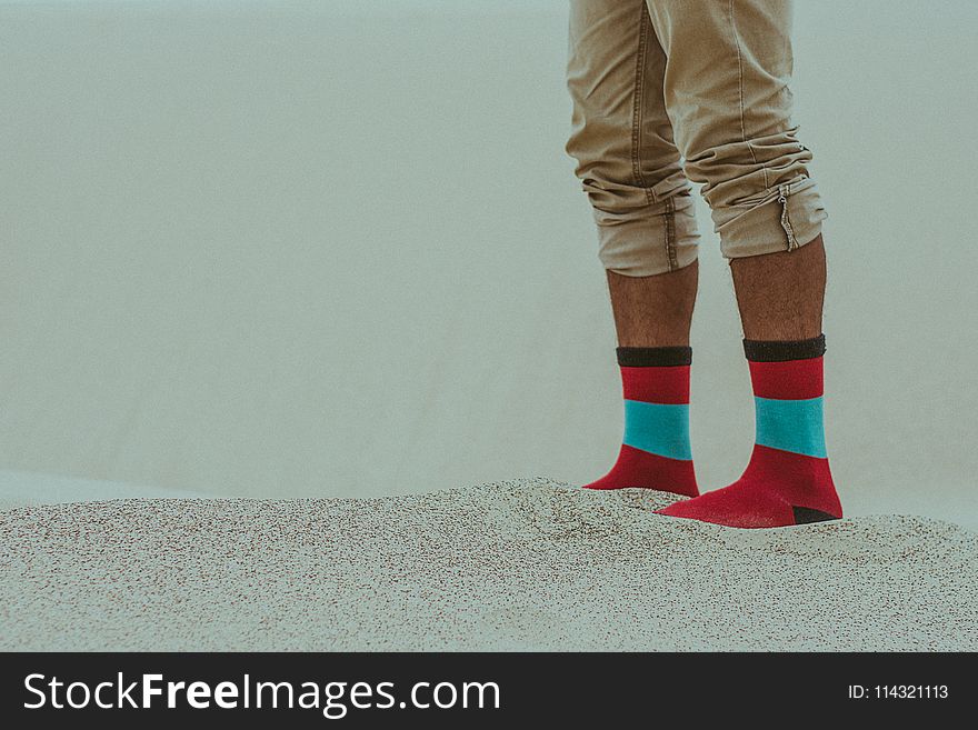 Person Wearing Red Socks Standing On Sand