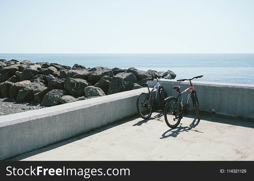 Two Bicycles Behind Gray Concrete Wall