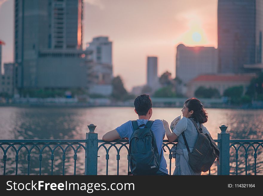 Couple Having Conversion Near Metal Fence During Golden Hour