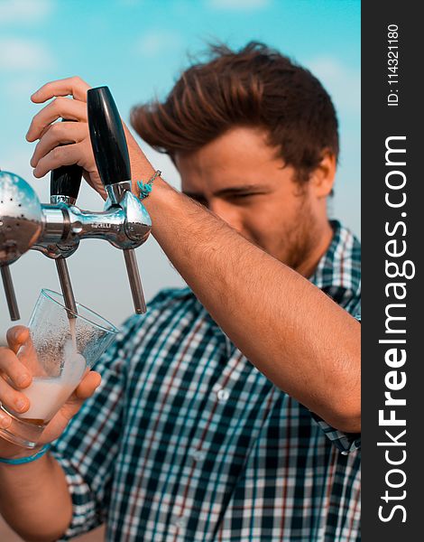 Man Holding Black Beer Tap Handle Pouring Beer on Clear Glass