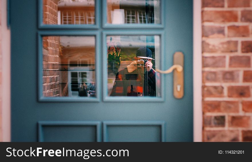 Man in Black Sweater Taking Photo of Blue Door