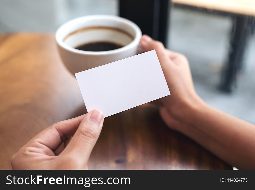 Hands holding an empty business card and coffee cup