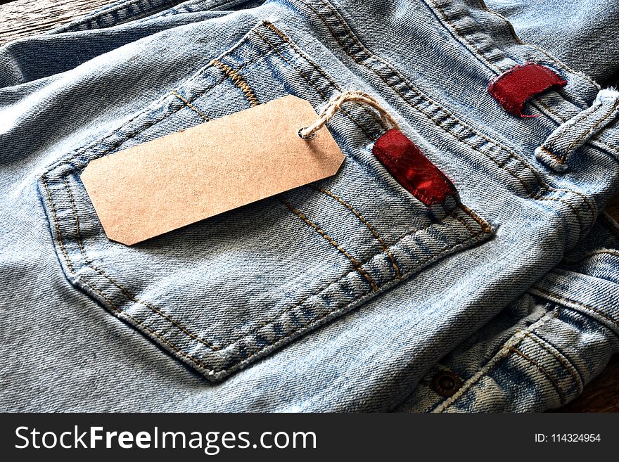 A close up image of a pair of denim jeans with a brown price tag. A close up image of a pair of denim jeans with a brown price tag.