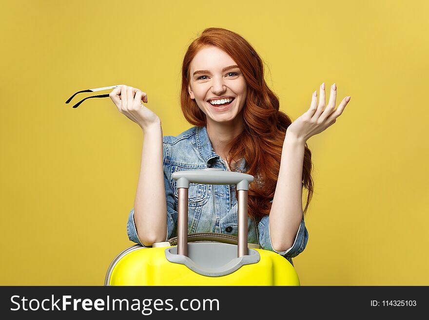 Travel Concept: Happy tourist woman wearing jean clothes ready for travel with suitcase and passport. Isolated over bright yellow background