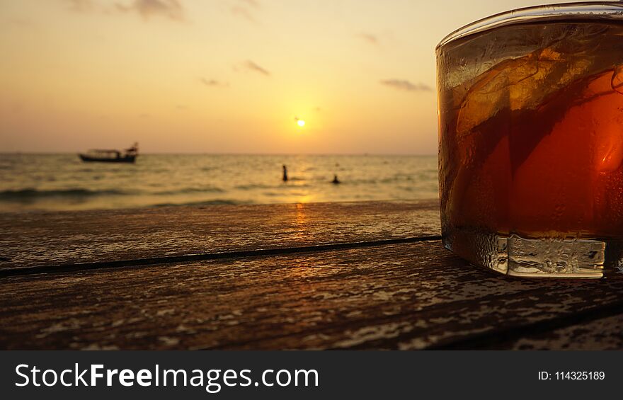 close up of a cocktail in front of tropical sunset. close up of a cocktail in front of tropical sunset