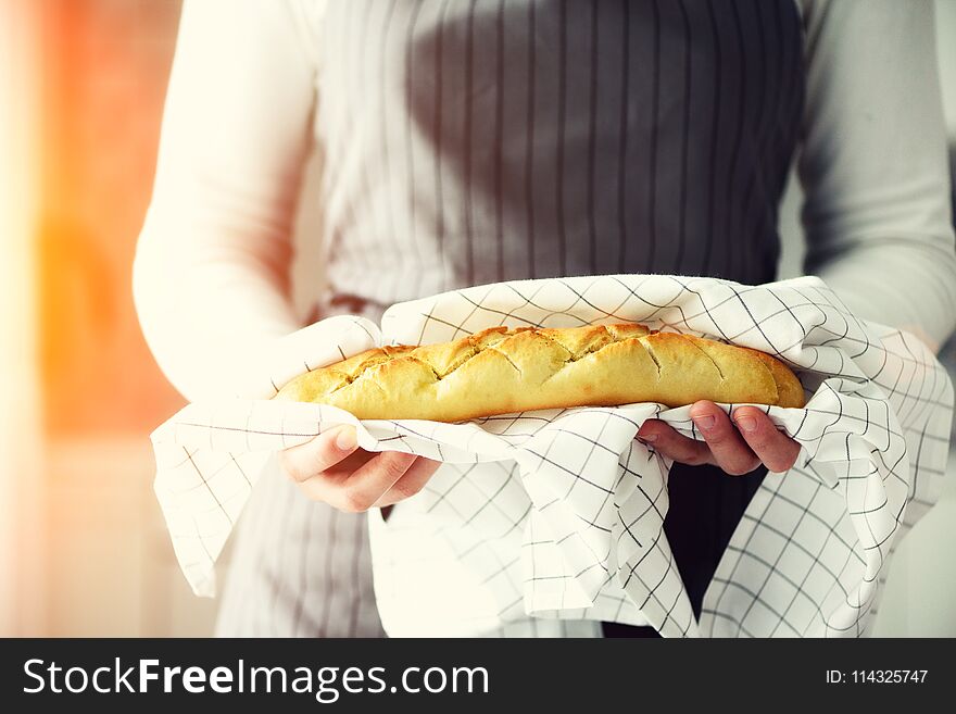 Woman hands holding freshly baked bread. French baguette, bakery concept, homemade food, healthy eating. Copy space