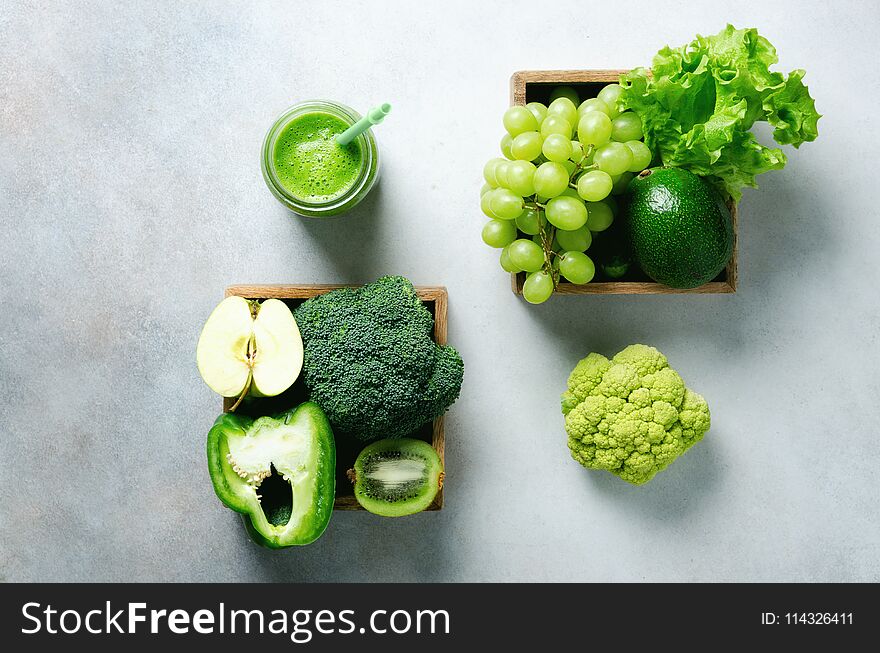 Green smoothie in glass jar with fresh organic green vegetables and fruits on grey background. Spring diet, healthy raw vegetarian, vegan concept, detox breakfast, alkaline clean eating. Copy space.