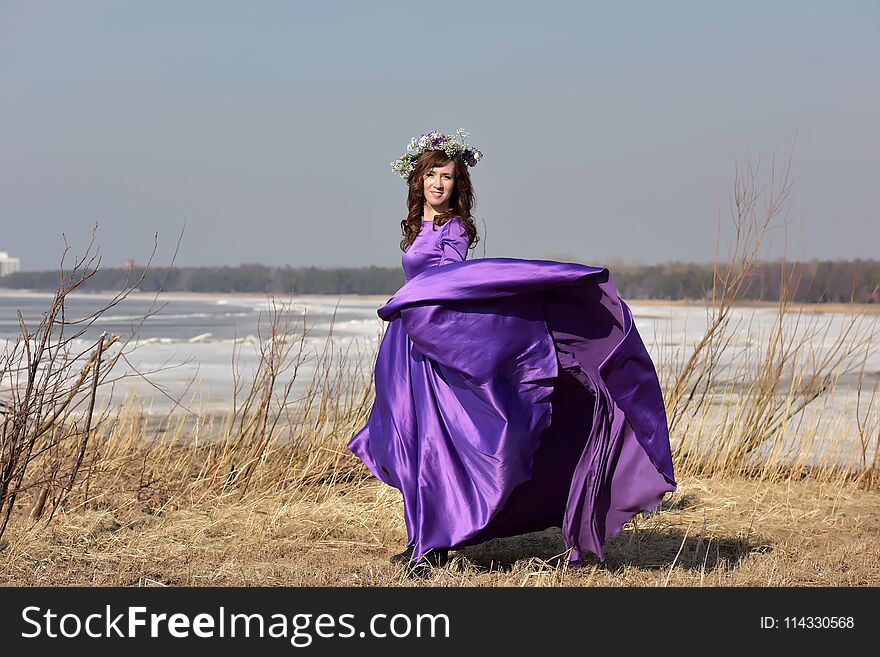 Woman lilac dress with a wreath of flowers on her head on nature
