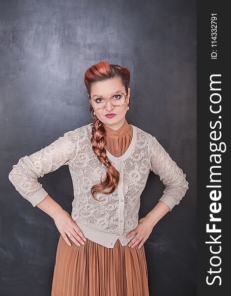 Serious teacher in glasses on the chalkboard blackboard background