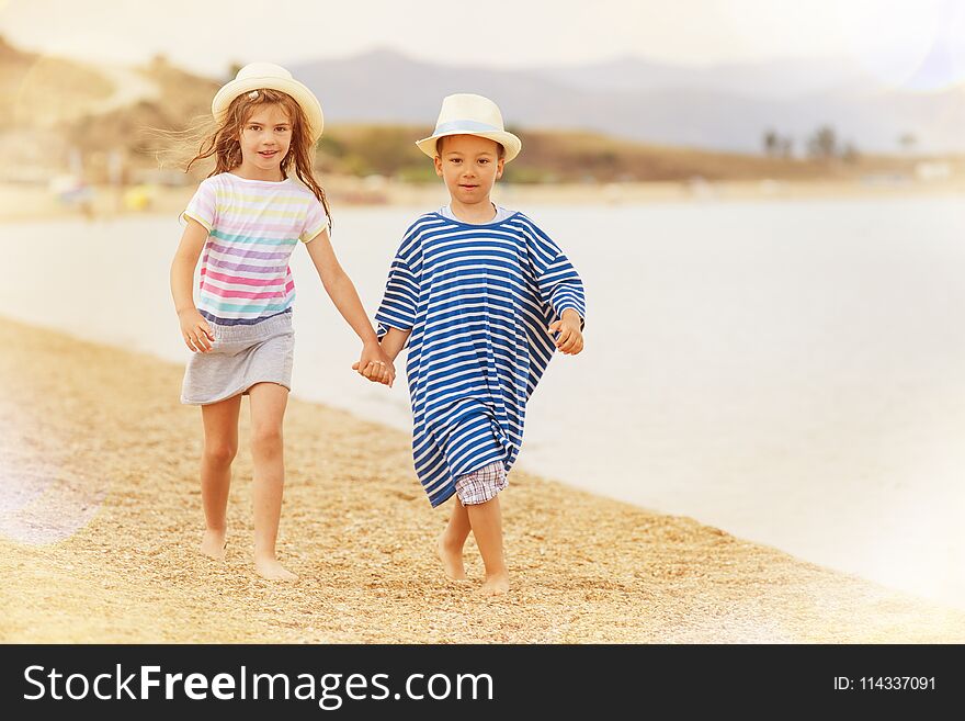 A boy and a girl around six holding hands while taking a walk on the beach smiling. A boy and a girl around six holding hands while taking a walk on the beach smiling.