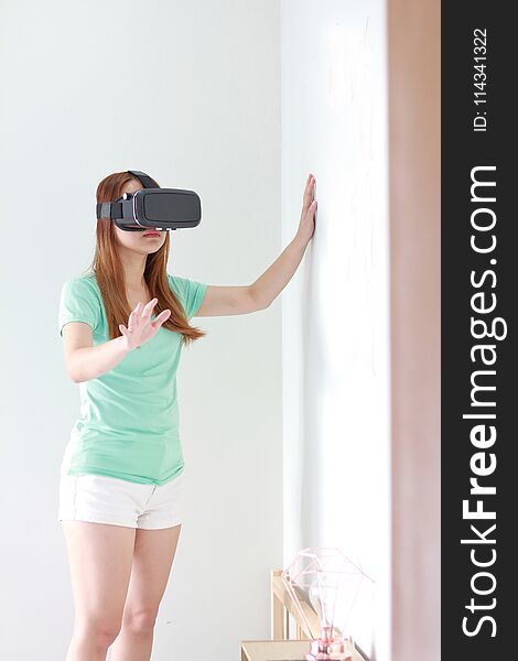 Young woman wearing virtual reality glasses at home.