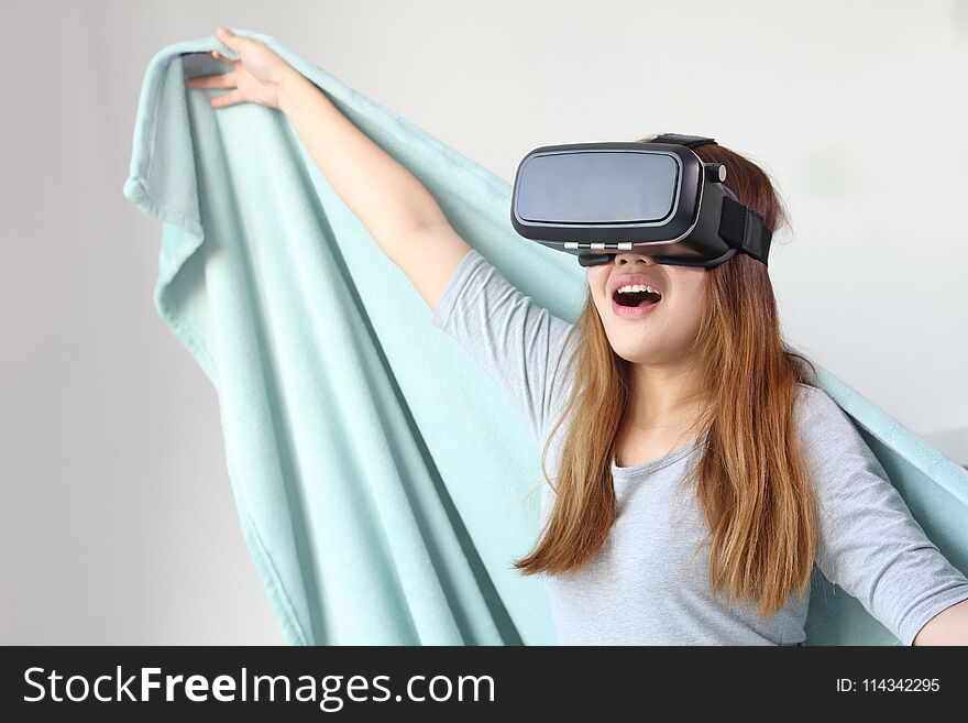 Young woman wearing virtual reality glasses at home. A virtual reality headset is a head-mounted device that provides virtual reality for the wearer.