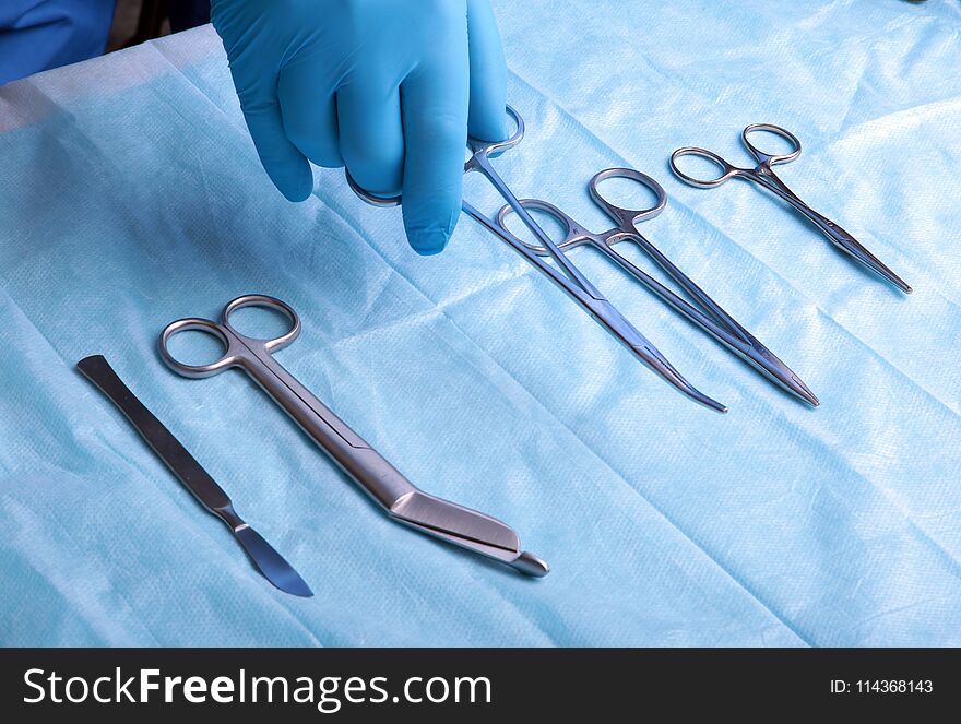 Detail shot of sterilized surgery instruments with a hand grabbing a tool