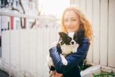 A Young Red-haired Caucasian Woman Holds A Small Funny Dog In The Arms Of Two Colors Of Black And White Chihuahua. Hugs And Kisses Stock Photos