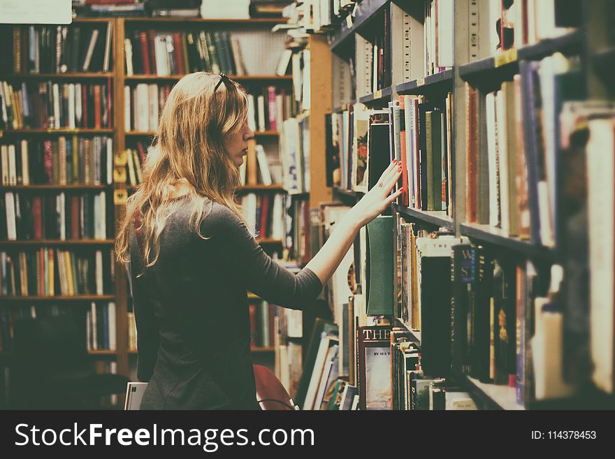 Woman in Black Long-sleeved Looking for Books in Library
