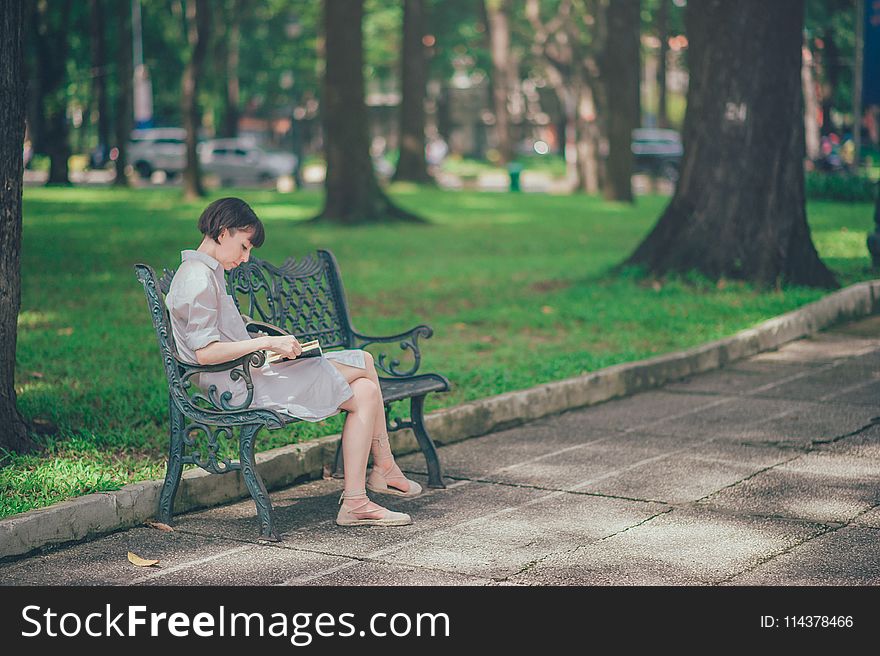 Photo of Woman Wearing Gray Dress Sitting on Bench