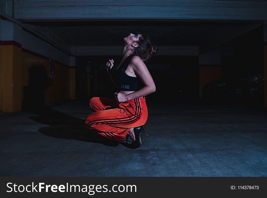 Woman in Black Crop Top Sitting on Concrete Floor