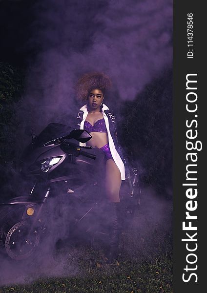 Woman Wearing Purple Bikini Riding On Sports Motorcycle With Smoke