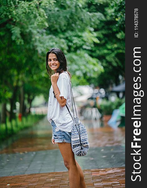 Shallow Focus Photography Of Woman In White Shirt And Blue Denim Shorts On Street Near Green Trees